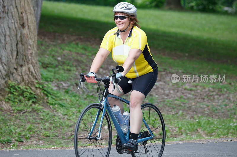 微笑的女人自行车骑手在公路自行车在公园