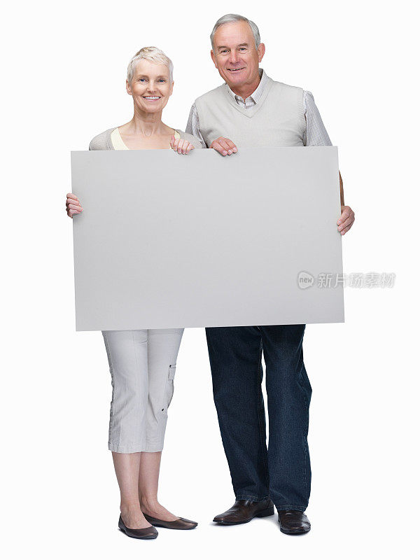 摄影棚拍摄的一对老年夫妇举着白色的空白广告牌