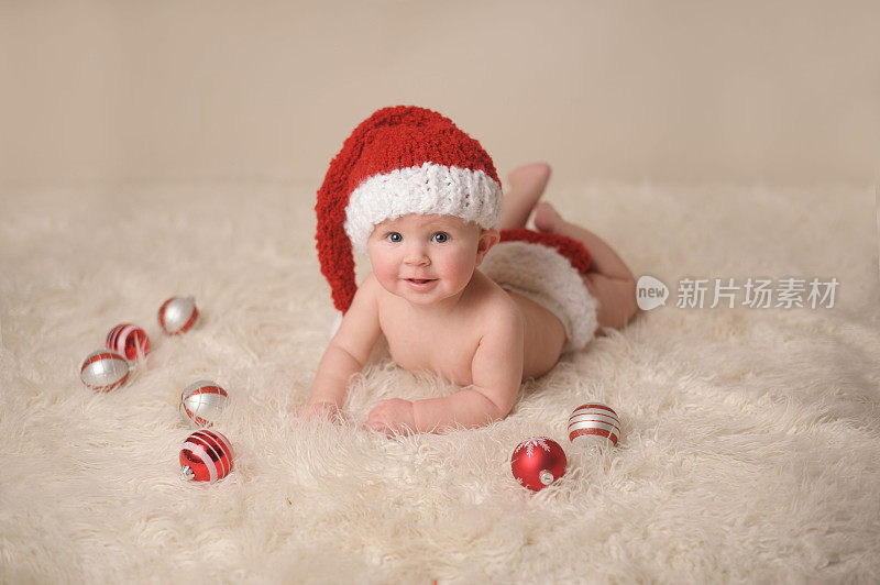 快乐的婴儿戴着圣诞帽和圣诞装饰品