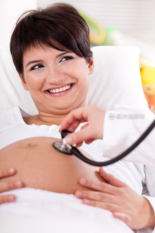 医生用听诊器听诊一位孕妇的腹部