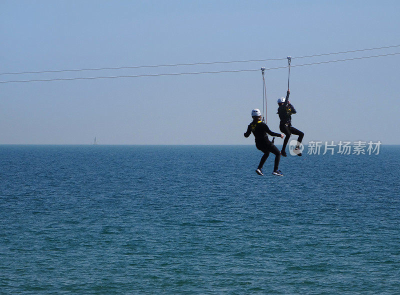 孩子们在海边的滑索上越过海水