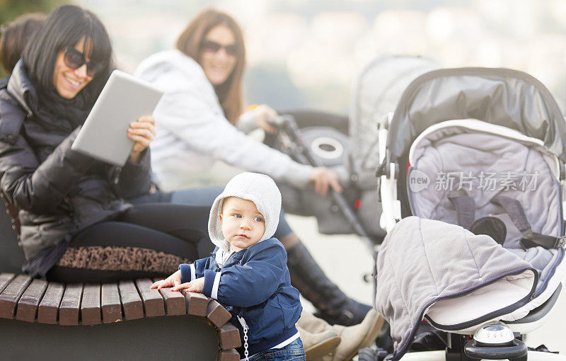 母亲们推着婴儿车在城市公园里休息