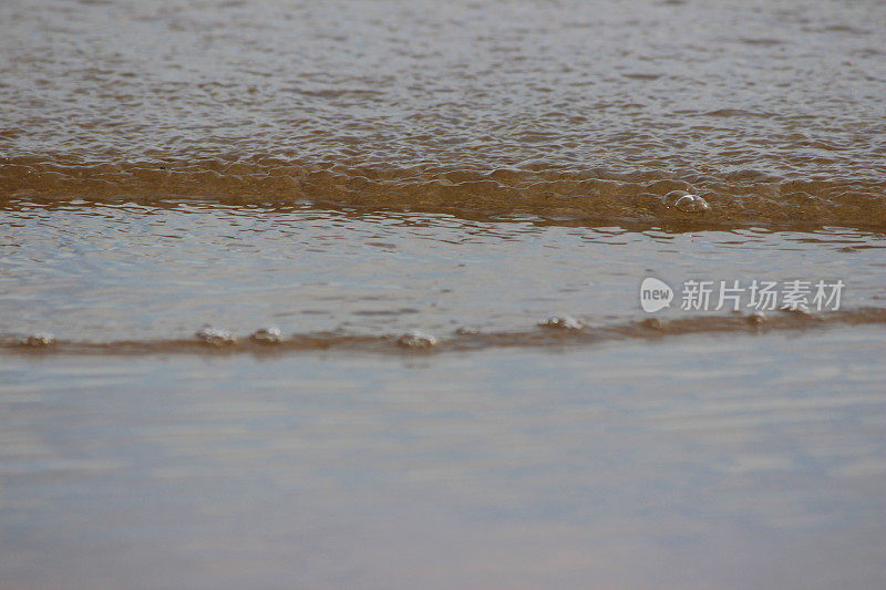 温柔的海浪拍打海滩海岸的特写图像