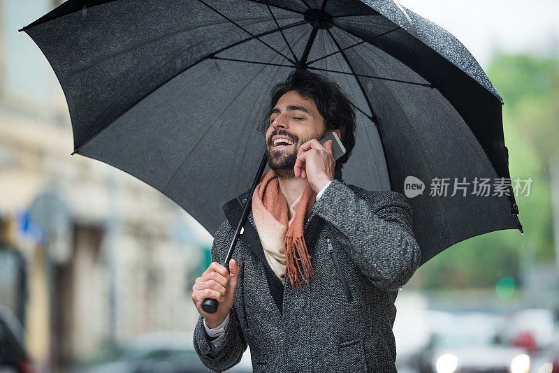 雨天带着雨伞和手机的男人