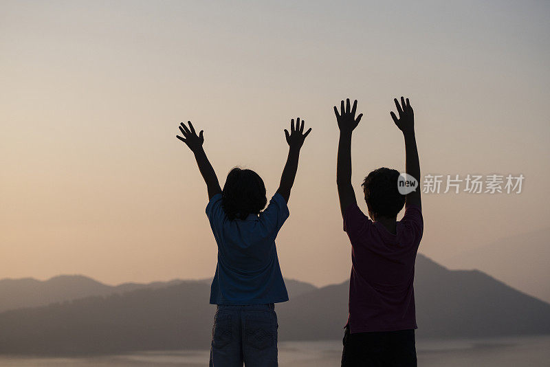 年轻男孩在湖边举起手臂的肖像