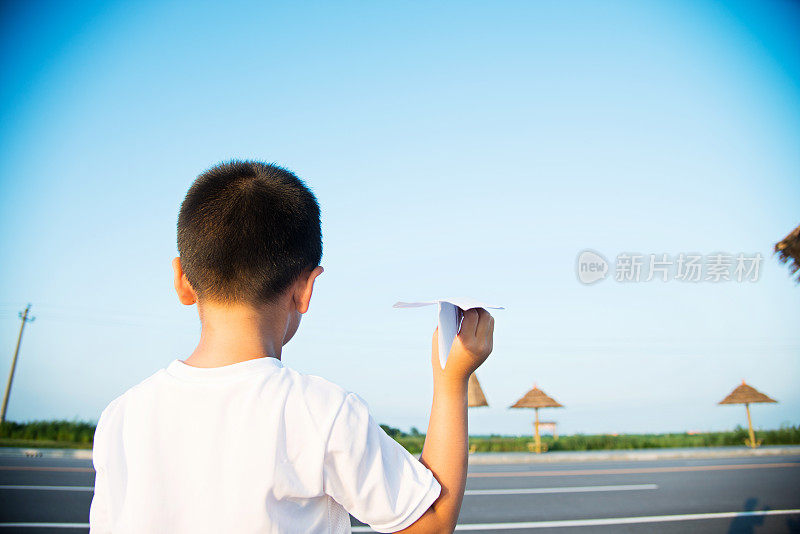 男孩手拿着纸飞机望着天空