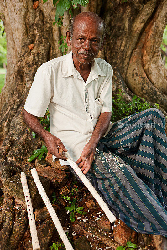 斯里兰卡人在木头上雕刻长笛。Polonnaruwa。