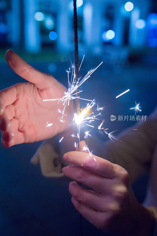 女人拿着圣诞烟花对着夜晚的街道