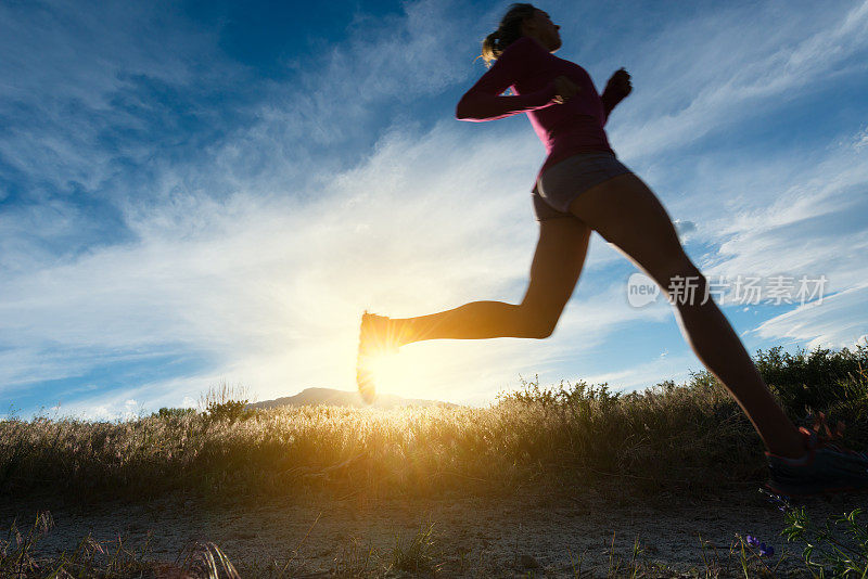 女人剪影越野跑者在日落在山