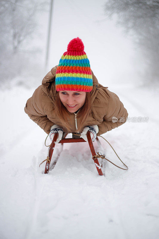 快乐的年轻女子在一个快速的雪橇骑下冰冷的斜坡