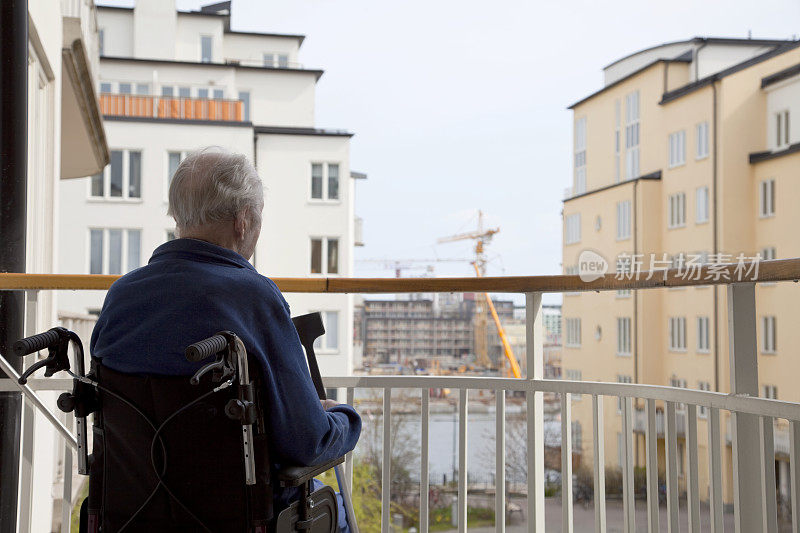 一个坐在轮椅上看外面世界的老人。