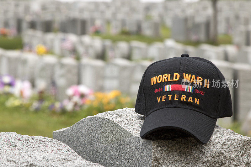 第二次世界大战的帽子坐在墓碑上，其他墓碑的背景