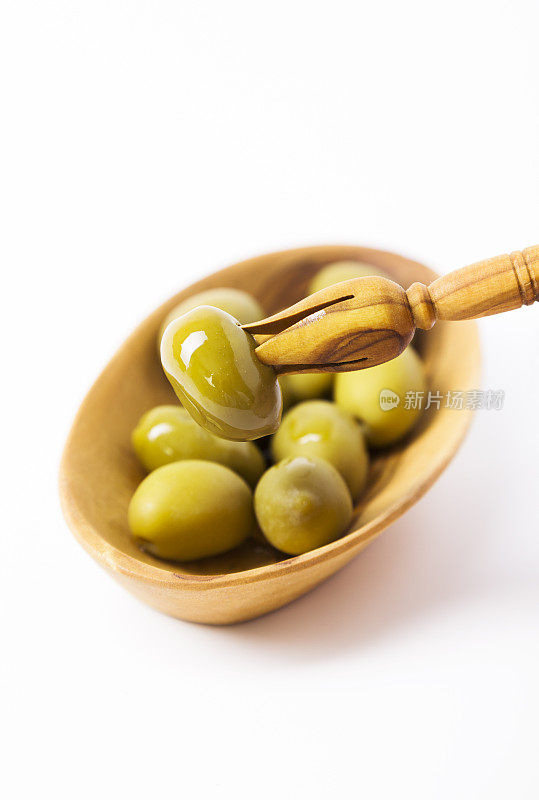 绿橄榄，橄榄油在橄榄木盘子。品尝。特写镜头。
