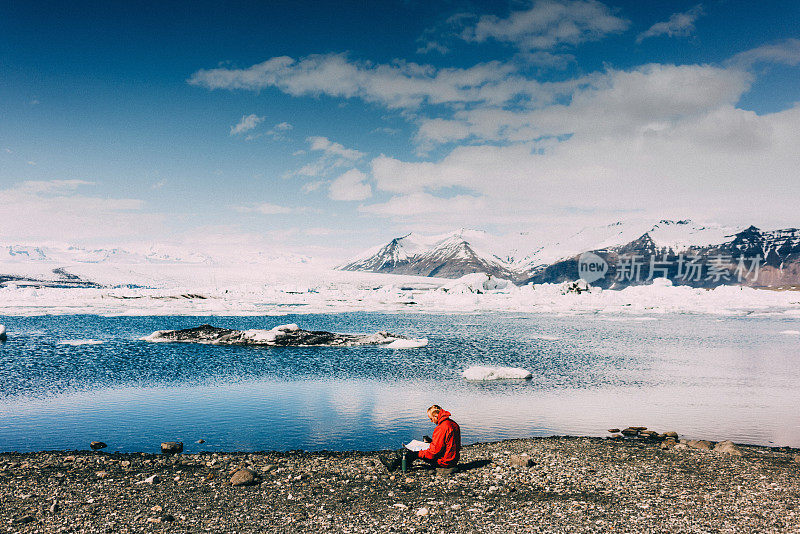 一个人坐在有冰川的湖边