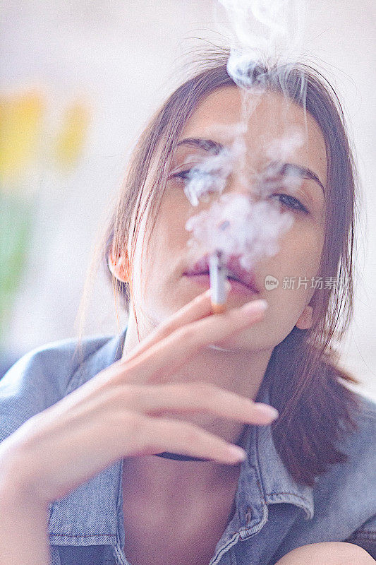 美丽叛逆的黑发女人在家里吸烟的肖像