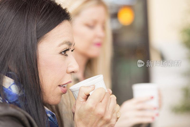 女性在户外咖啡馆使用手机。