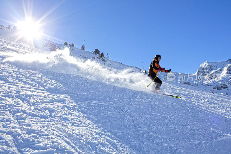 在西班牙比利牛斯的一个阳光明媚的日子里，一名滑雪者从山上疾驰而下