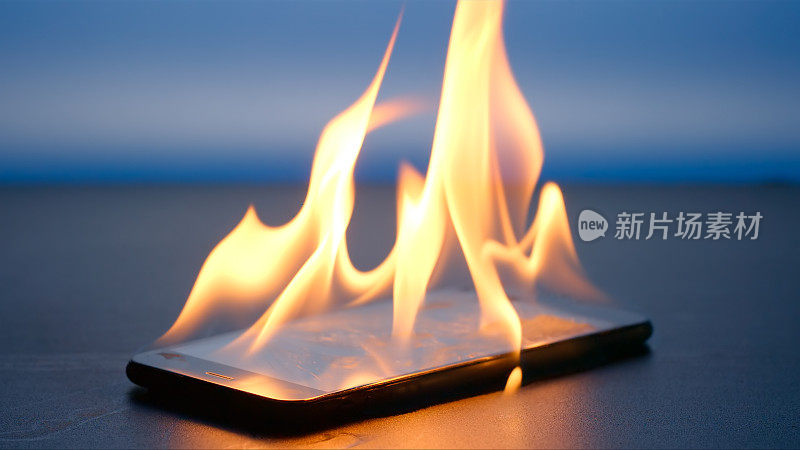蓝色背景的桌子上，智能手机正在燃烧