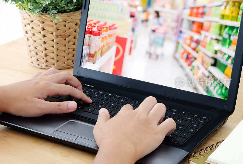 手打字笔记本模糊超市屏幕上，杂货店在线概念，业务和技术