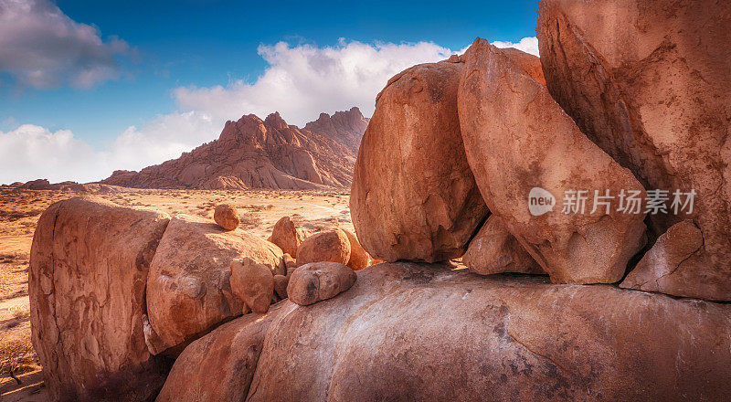 巨大的花岗岩巨石不同大小的前景与山在背景。纳米比亚纳米布沙漠的斯匹茨科普。