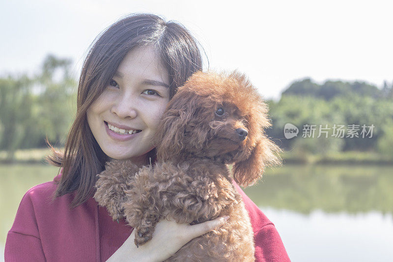 女人在湖边拥抱宠物狮子狗的特写