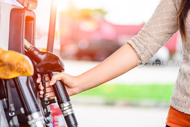 一个女人的手在一个加油站的燃油泵的特写。