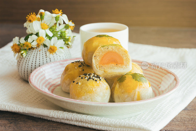 在侧面的木桌上放着美味的中式点心或月饼，里面包着绿豆沙和咸蛋黄。自制的面包店的概念。