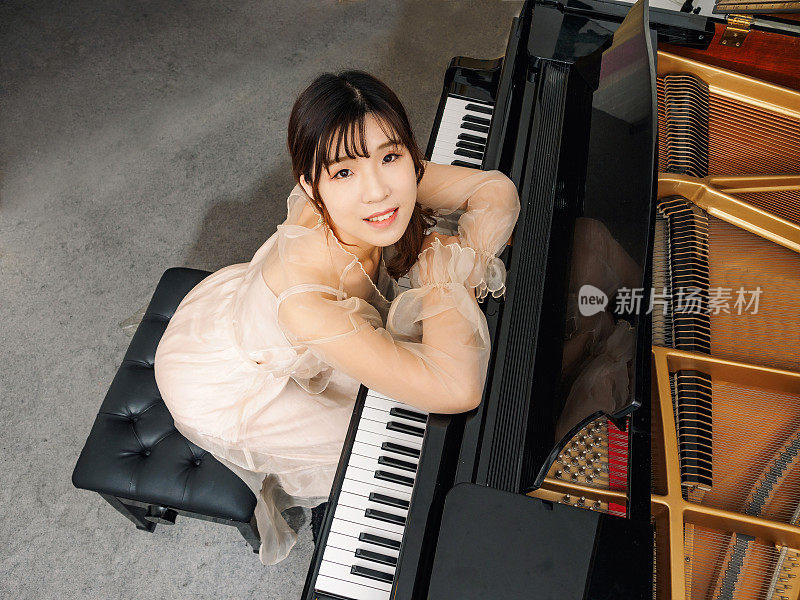 中国女孩和大钢琴。漂亮的年轻女孩钢琴家。