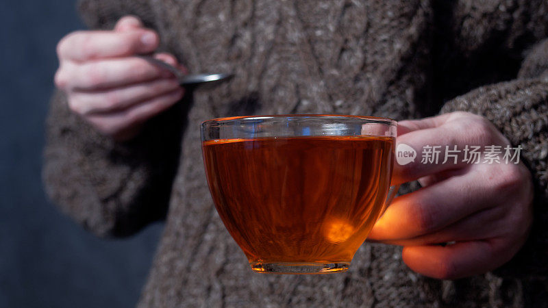 人的手拿着茶杯和茶匙