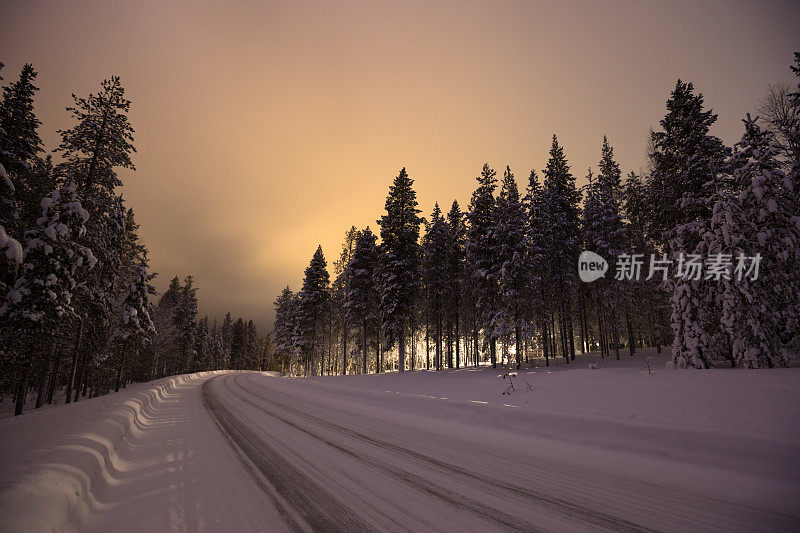 主要道路覆盖着雪和美丽的黎明前的曙光在天空中