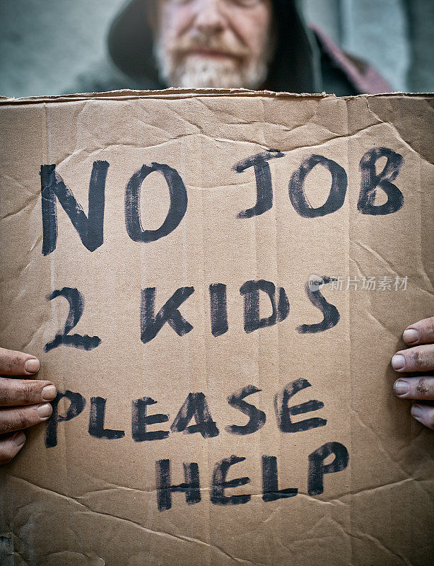 无家可归的乞丐的牌子上写着“没有工作，两个孩子，请帮忙”