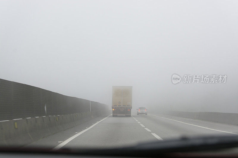 一辆卡车在浓雾中在双车道上超车。