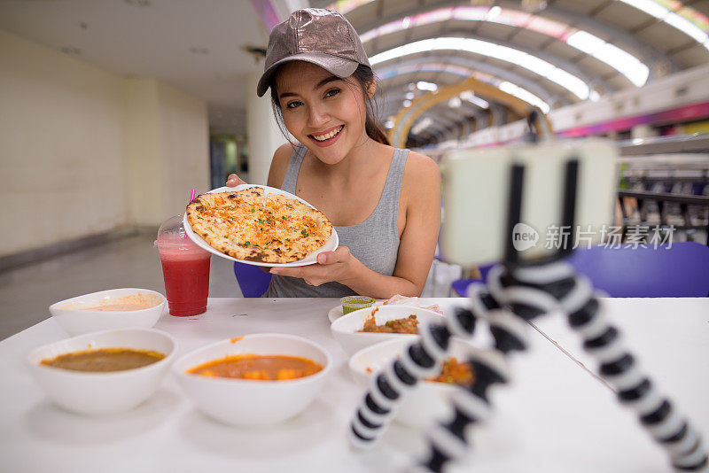 年轻美丽的亚洲女游客在餐厅享受印度美食的肖像