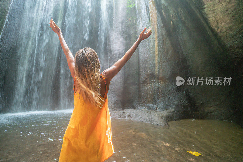 在巴厘岛的热带雨林中，旅行的年轻女子张开双臂拥抱大自然的美丽。人们以自然为旅游理念。