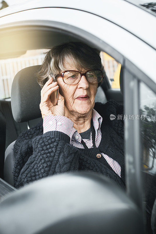 在车里打电话的资深女士焦急地皱着眉头