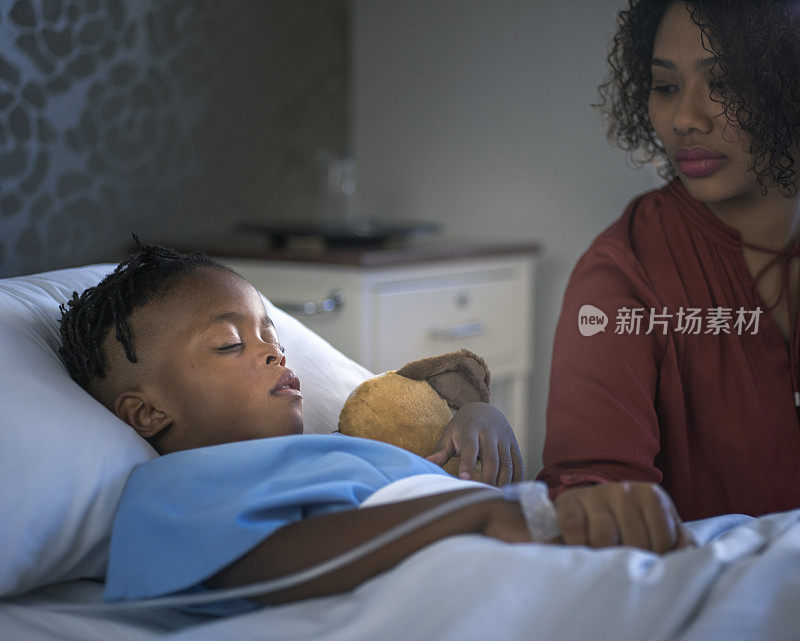 年轻的母亲在病房里看着生病的儿子