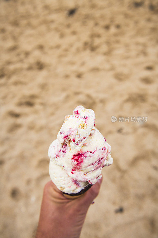 在Fistral海滩，纽基，康沃尔，手持一个大覆盆子涟漪冰淇淋。