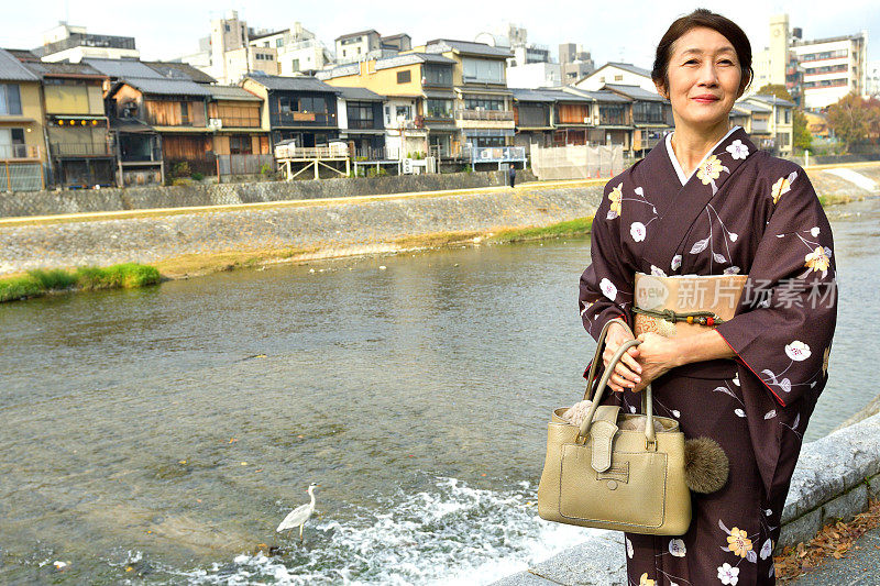 穿着和服的日本妇女在京都的秋天沿着加茂河行走