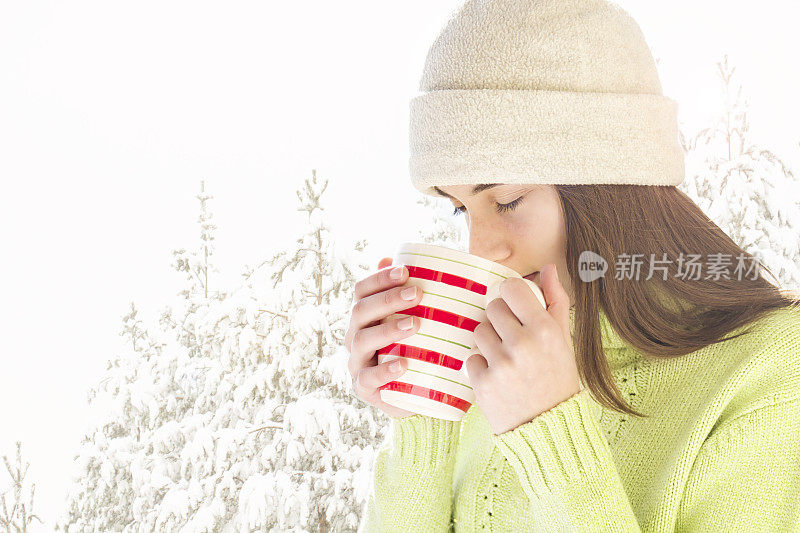 年轻女子与一杯热饮在雪天的冬天