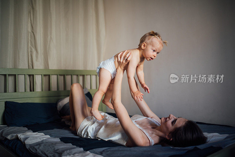 快乐的家庭妈妈和宝宝在床上玩耍和拥抱