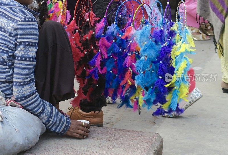 印度无家可归的孩子在街头市场上出售彩色捕梦网作为纪念品礼物，康诺特广场照片，新德里，印度