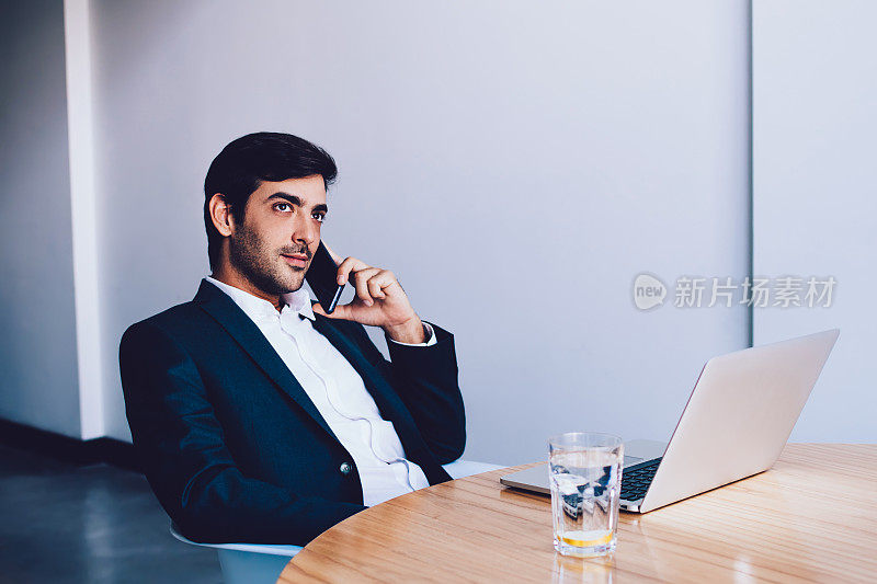 严肃的男性主管通过手机进行重要对话，花时间在公司办公室，印度it专业人员用笔记本电脑打电话给雇主讨论细节