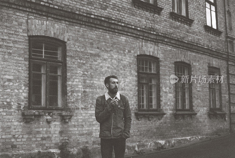 一个男人站在老建筑附近的黑白胶片照片