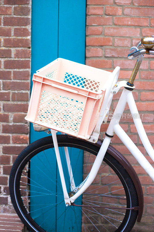 荷兰:红色砖墙上停放着一辆粉色板条箱的自行车