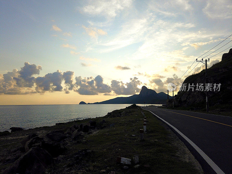 越南孔岛的空旷蜿蜒的乡村公路全景。日落时的汽车旅行。蓝天，云和山。Condao岛屿。