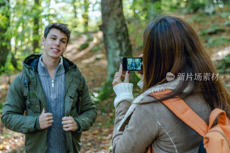 一对年轻的徒步旅行者在树林里用智能手机拍照