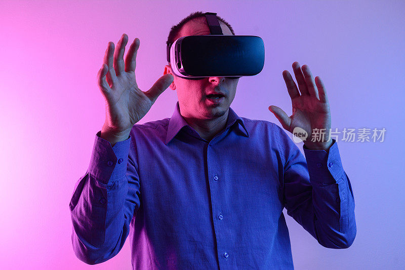 帅哥用VR眼镜或3d眼镜玩电子游戏，戴着虚拟现实头戴式眼镜为他戴上霓虹灯