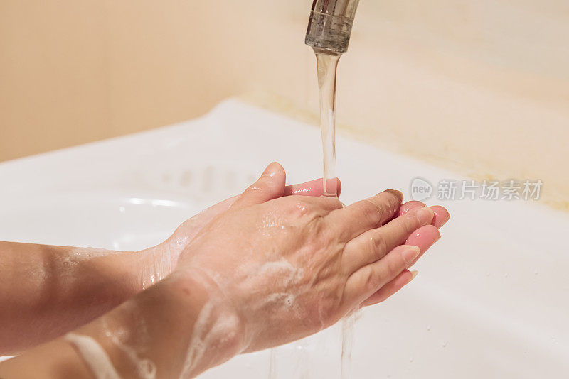 在水龙头下用肥皂洗手的妇女照片