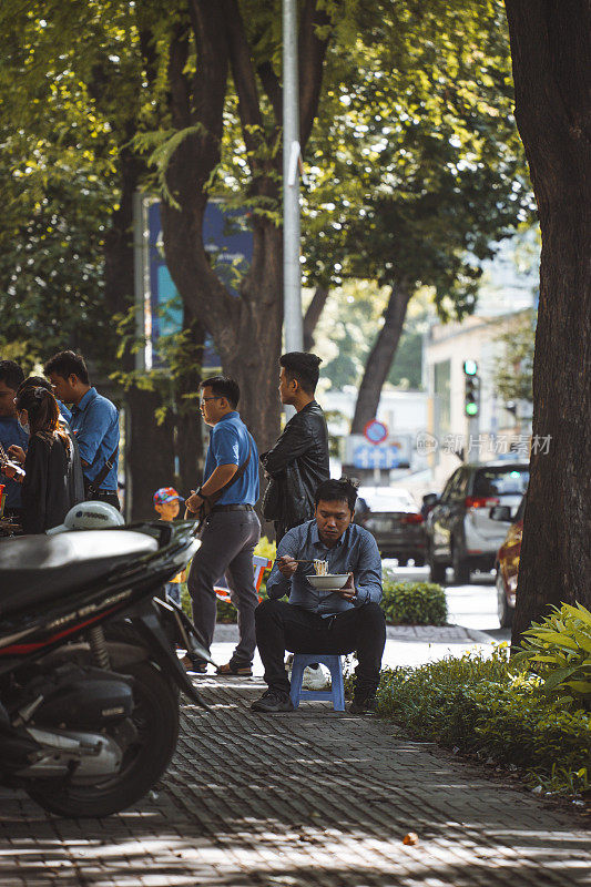 西贡(胡志明市)的街道上，人们在人行道上吃早餐的情景。
