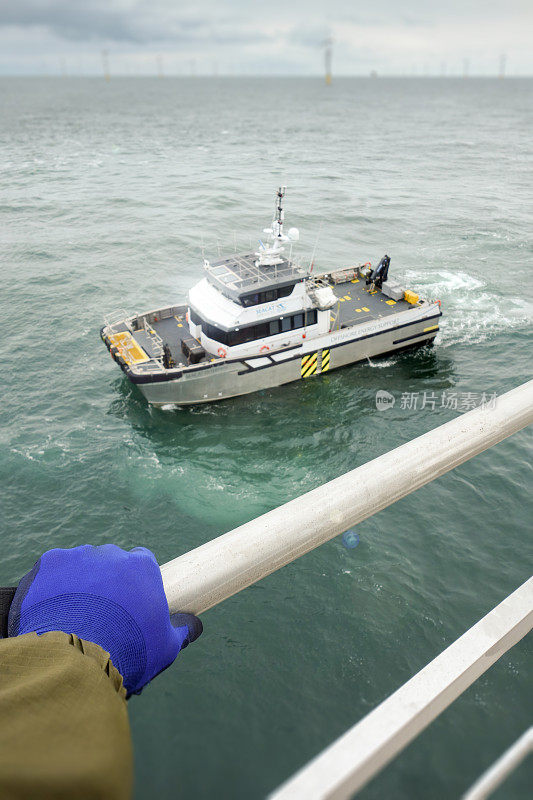 手握住栏杆。技术人员在海上平台上等待转移船-风力涡轮机。到北海接技术人员的中转船。